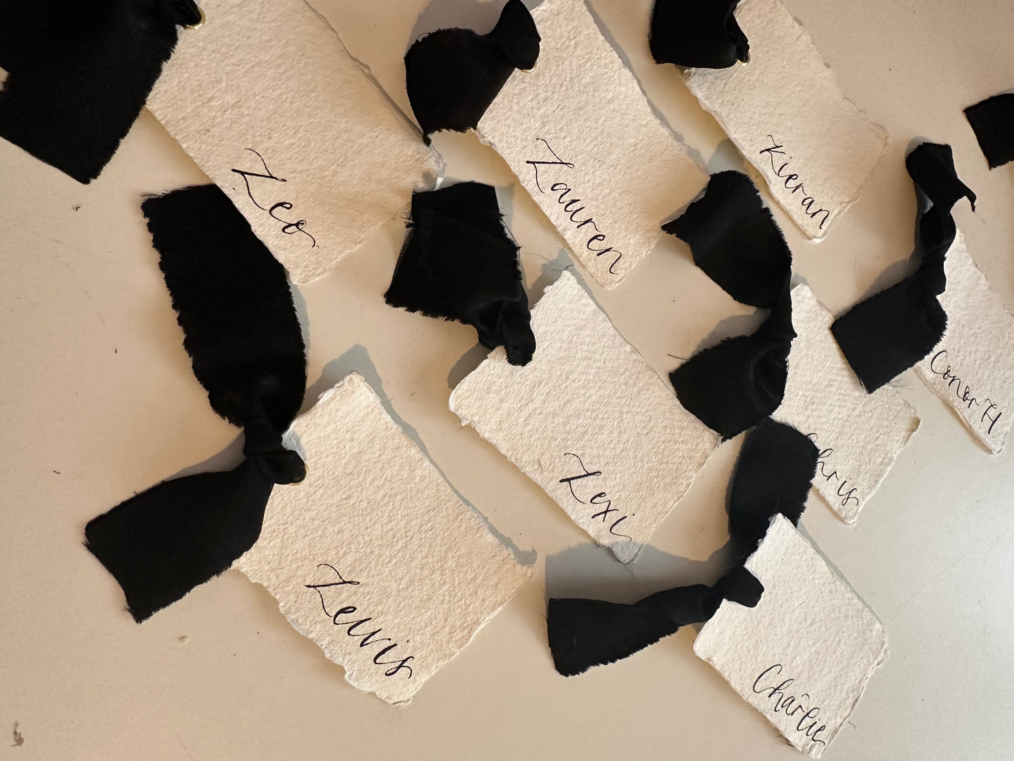 handwritten place cards on handmade paper with black ribbon