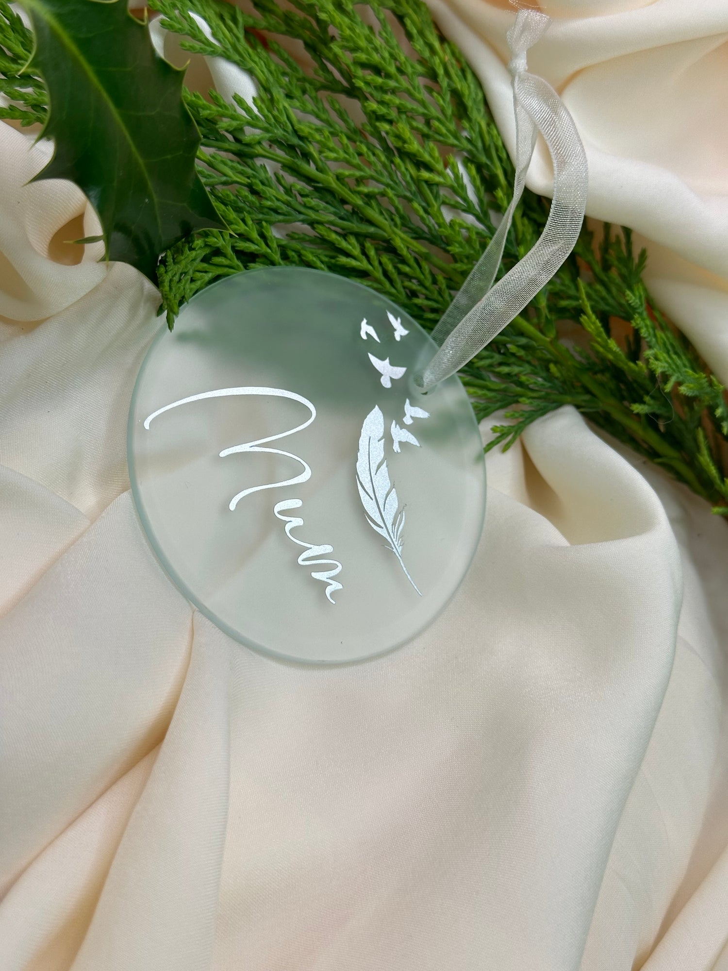 "Glass Christmas tree ornament featuring a silver design with a white feather and flying doves, symbolizing remembrance for a lost mum."