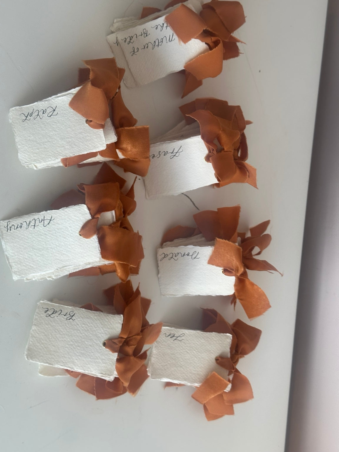 Ivory handmade paper place cards with ochre chiffon ribbon and handwritten calligraphy