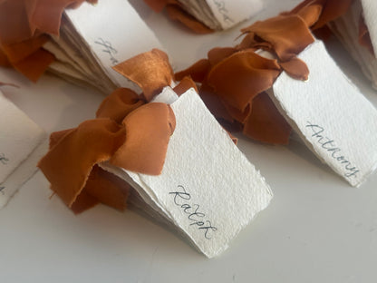 Ivory handmade paper wedding place cards with ochre chiffon ribbon