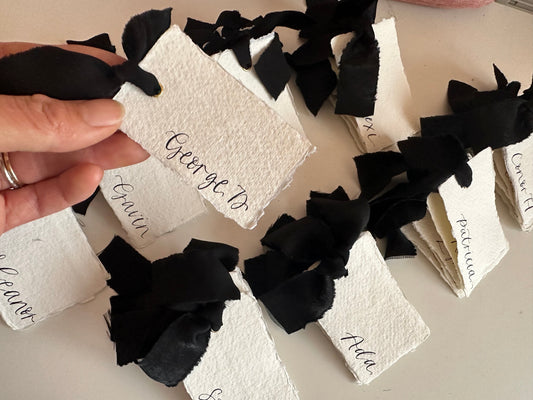 handwritten place cards on handmade paper with black ribbon