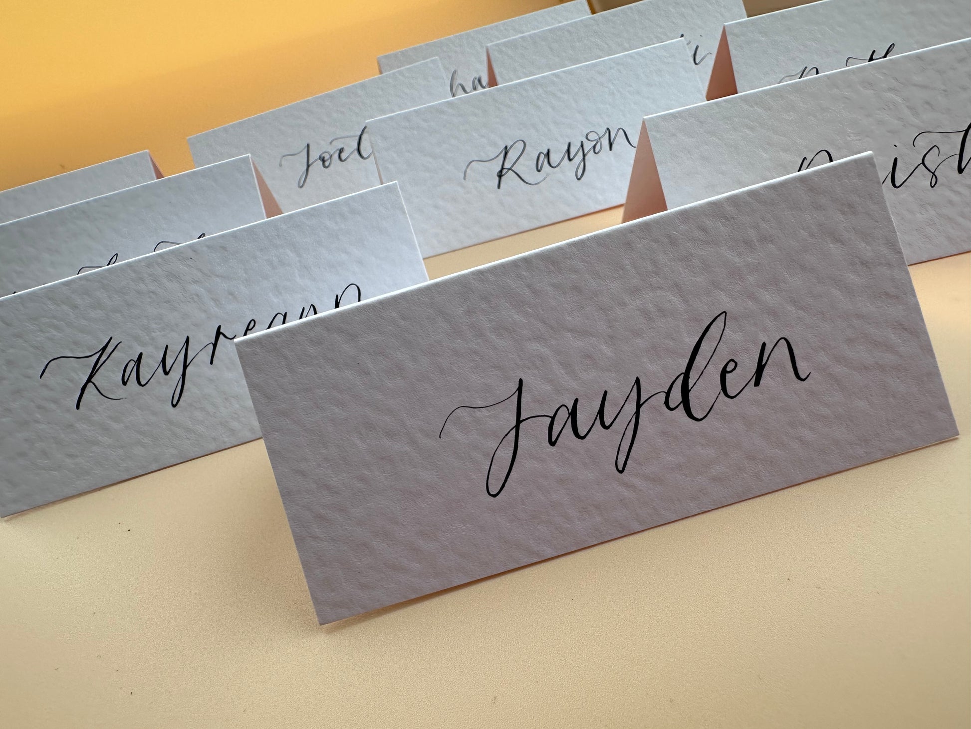 hammered paper, wedding place card, rustic wedding stationery, elegant table decor, handmade place cards, custom calligraphy, unique wedding details, vintage wedding theme, personalized place settings, textured paper cards, custom card stock, artisan wedding stationery, affordable wedding place cards, DIY wedding projects, modern calligraphy for events