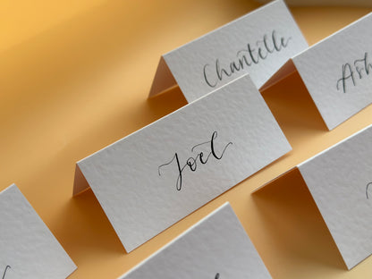 hammered paper, wedding place card, rustic wedding stationery, elegant table decor, handmade place cards, custom calligraphy, unique wedding details, vintage wedding theme, personalized place settings, textured paper cards, custom card stock, artisan wedding stationery, affordable wedding place cards, DIY wedding projects, modern calligraphy for events