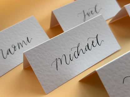 hammered paper, wedding place card, rustic wedding stationery, elegant table decor, handmade place cards, custom calligraphy, unique wedding details, vintage wedding theme, personalized place settings, textured paper cards, custom card stock, artisan wedding stationery, affordable wedding place cards, DIY wedding projects, modern calligraphy for events