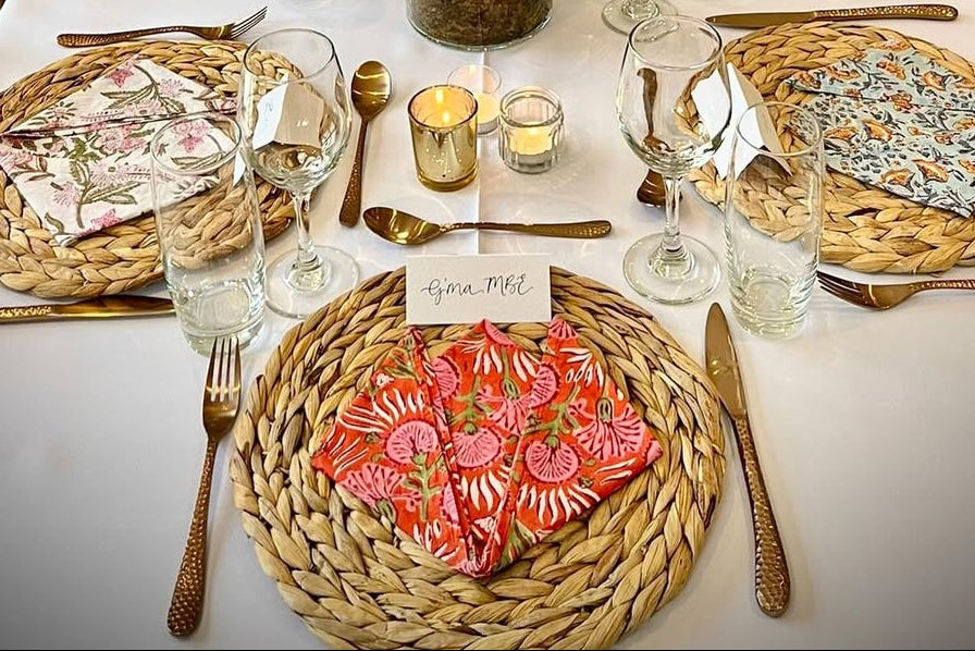 Dining table set with tented place cards, glasses, and centrepieces in a dinner party setting.
