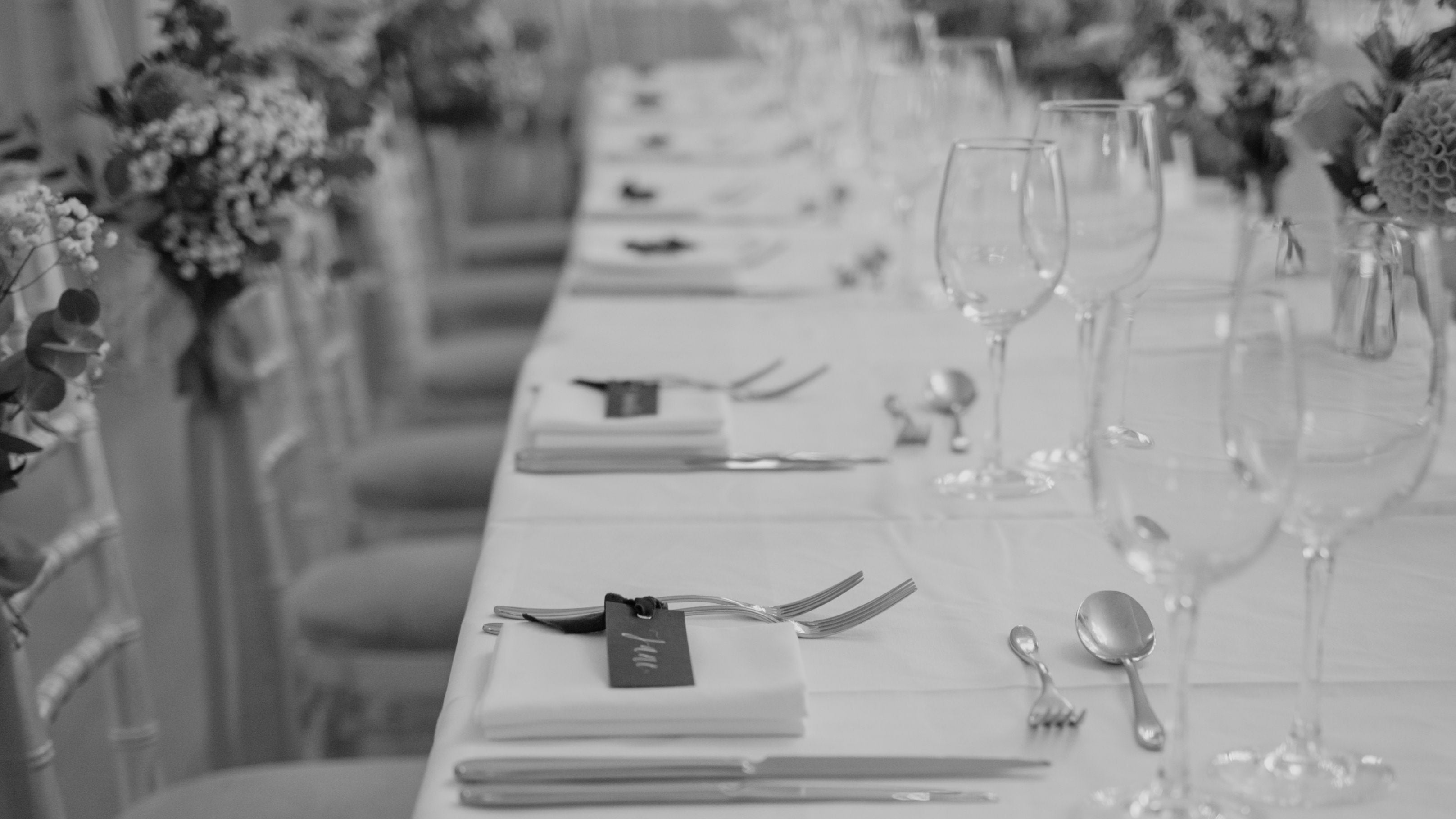 Long table set for a formal event with place settings and floral decorations.