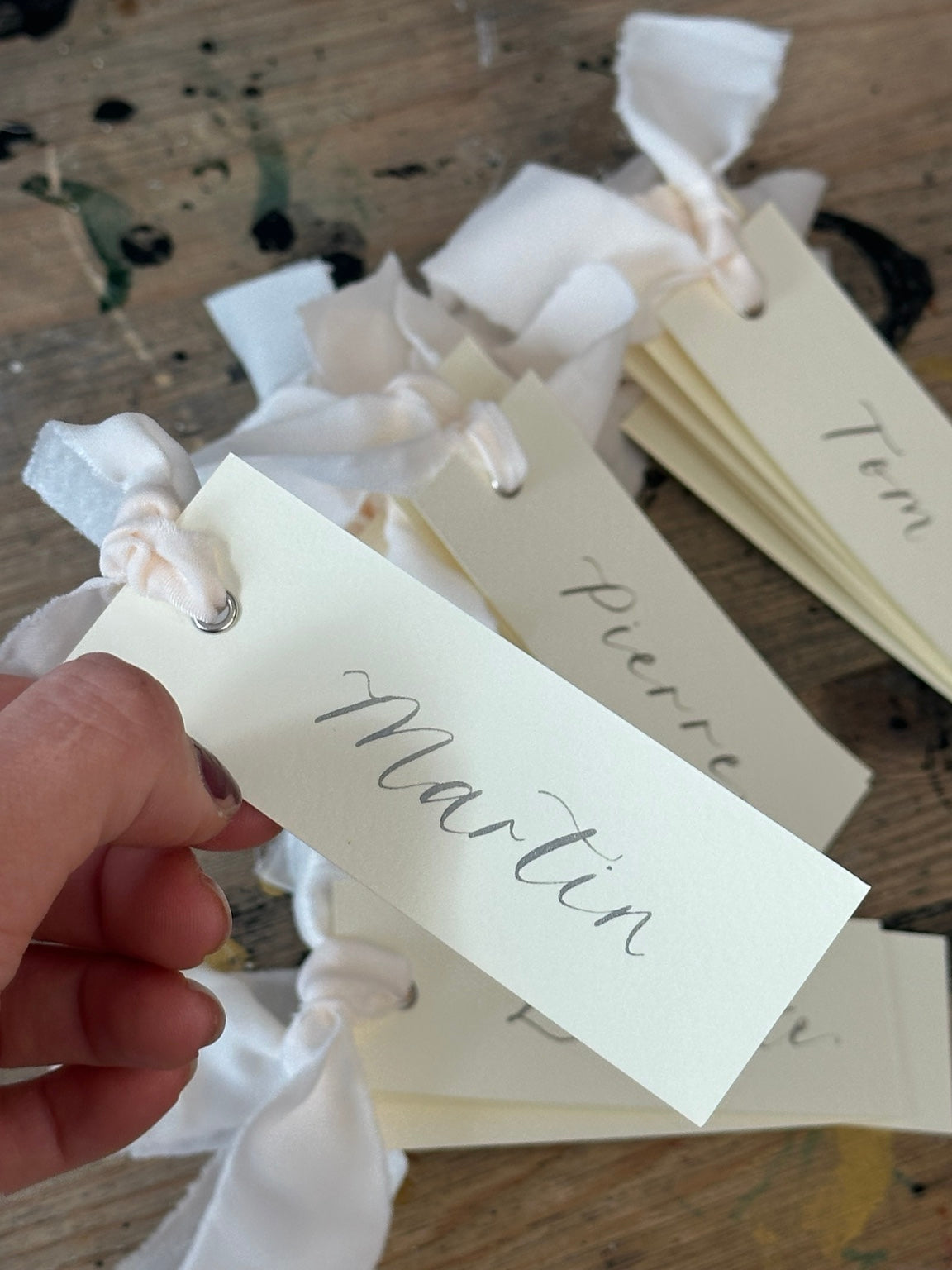 Ivory calligraphy wedding place card with champagne ribbon, silver ink and silver eyelet