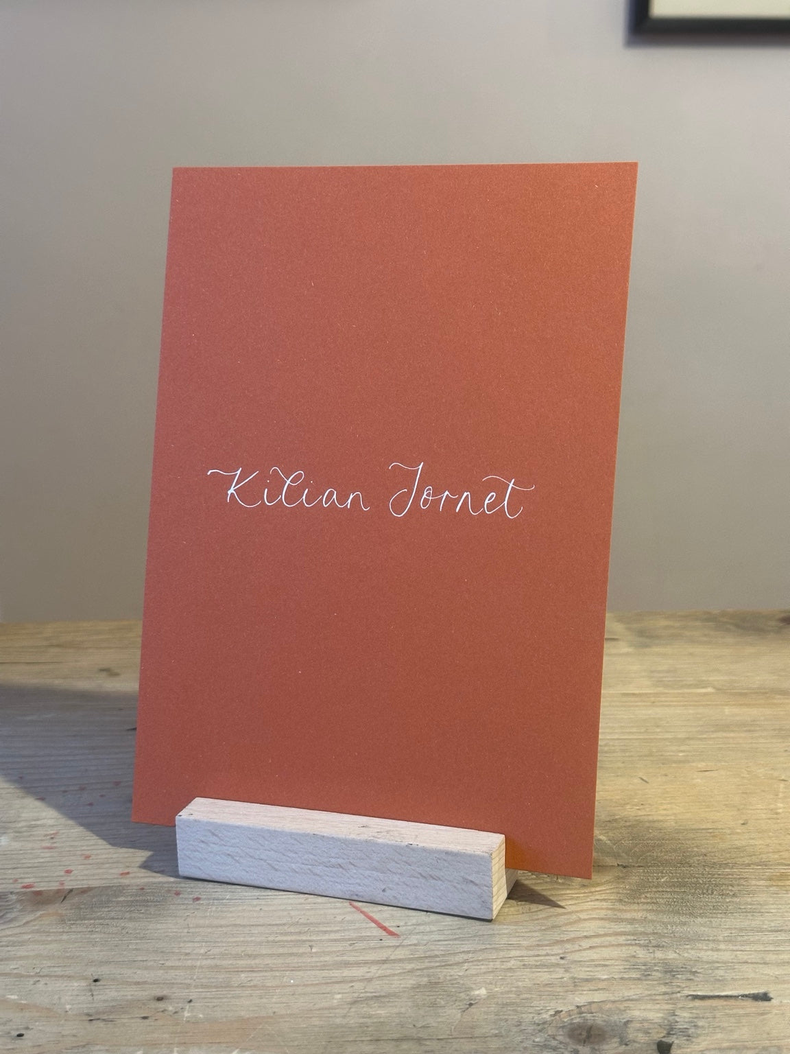 Colourful ochre wedding table name sign with white handwritten calligraphy, no ribbon