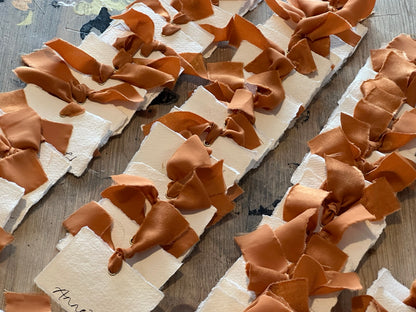 Handmade cotton rag place cards finished with ochre ribbon and gold eyelets, arranged together