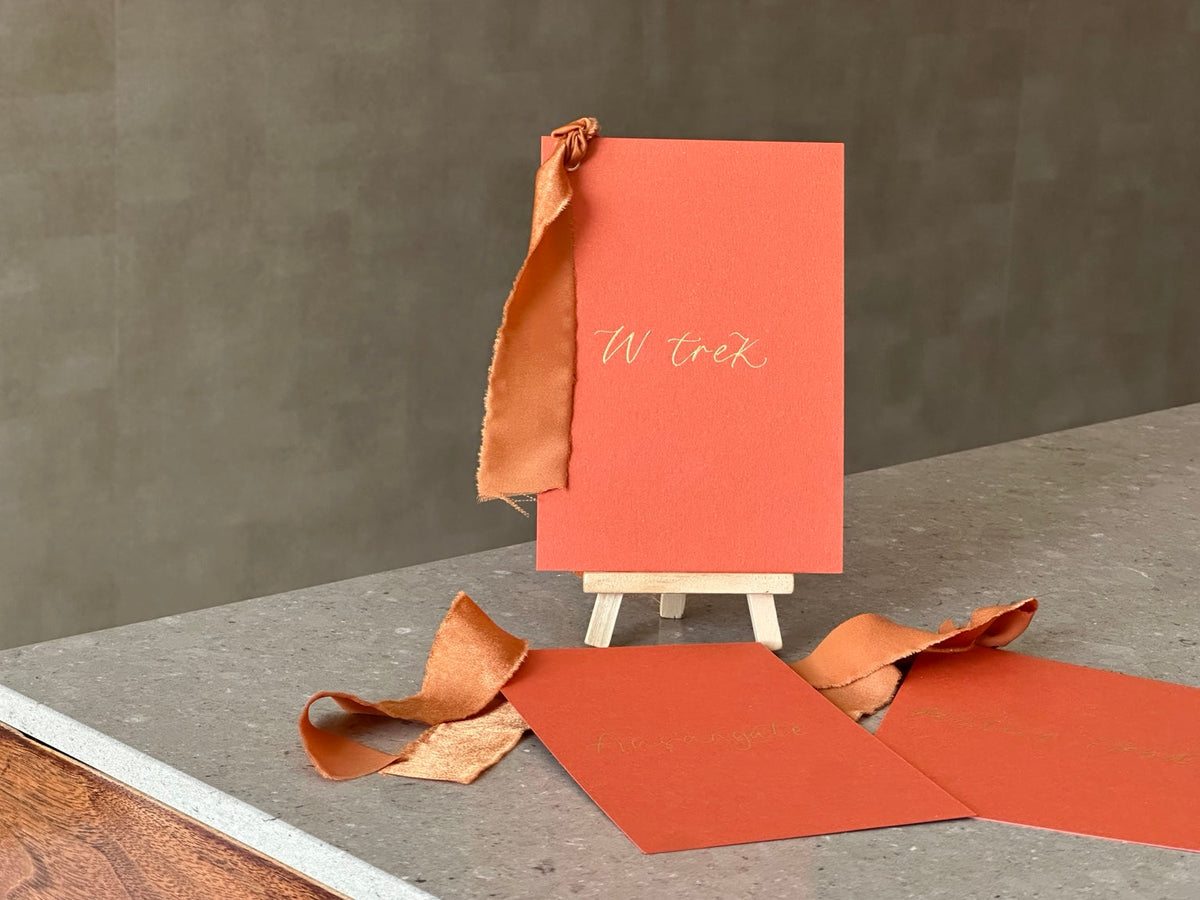 Ochre calligraphy wedding table name card with ribbon on easel