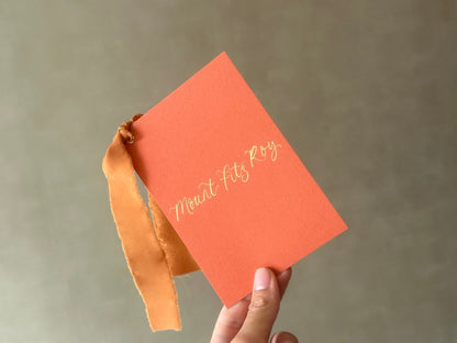 Handheld ochre calligraphy wedding table name card with ribbon