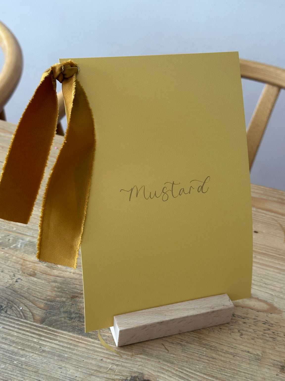Mustard yellow wedding table name sign with matching ribbon and calligraphy