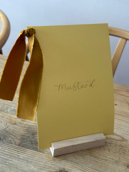 Mustard yellow wedding table name sign with matching ribbon and calligraphy