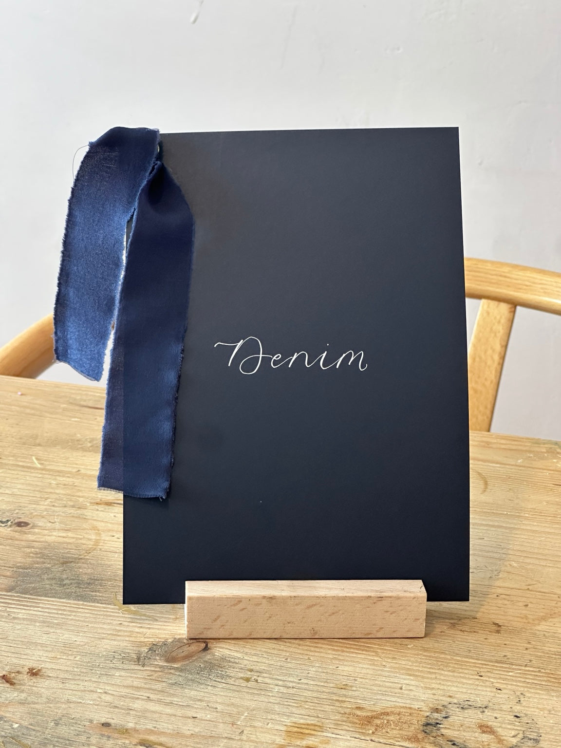 Navy wedding table name sign with blue ribbon and white calligraphy