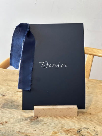 Navy wedding table name sign with blue ribbon and white calligraphy