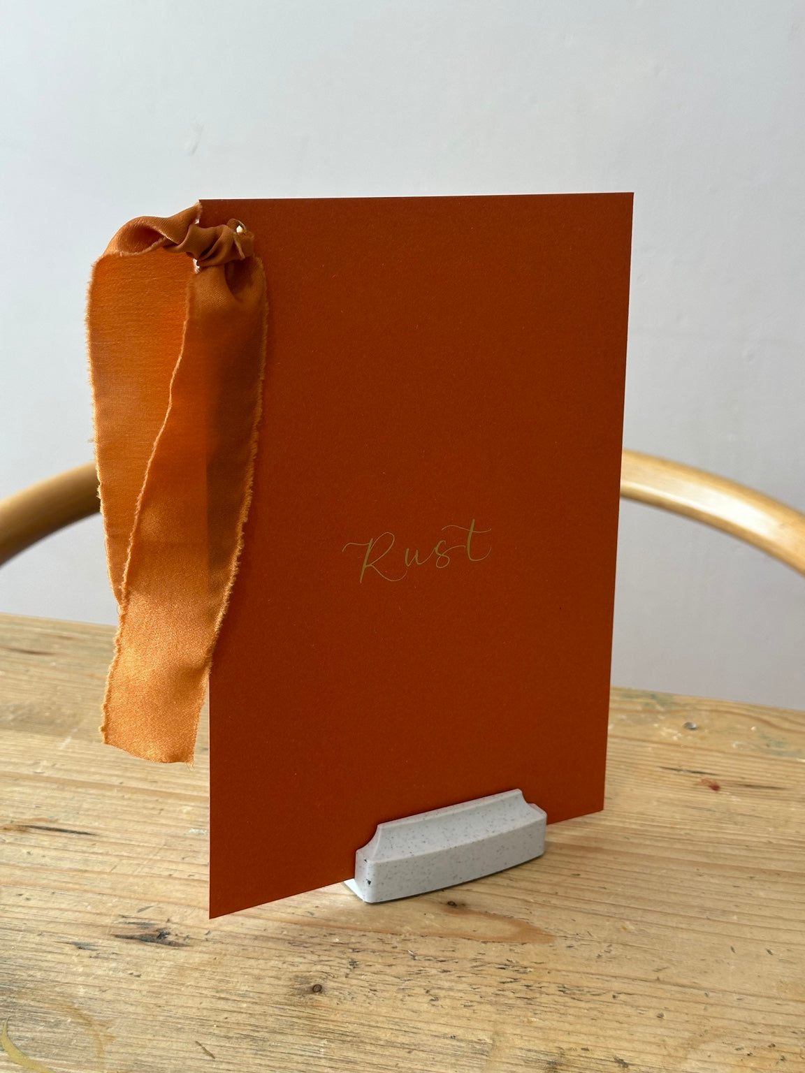 Rust wedding table name sign with rust ribbon and gold calligraphy