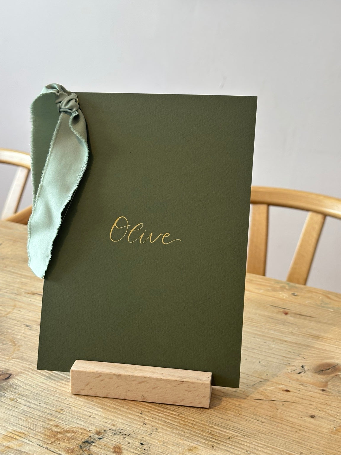 Olive green wedding table name sign with sage ribbon and gold calligraphy