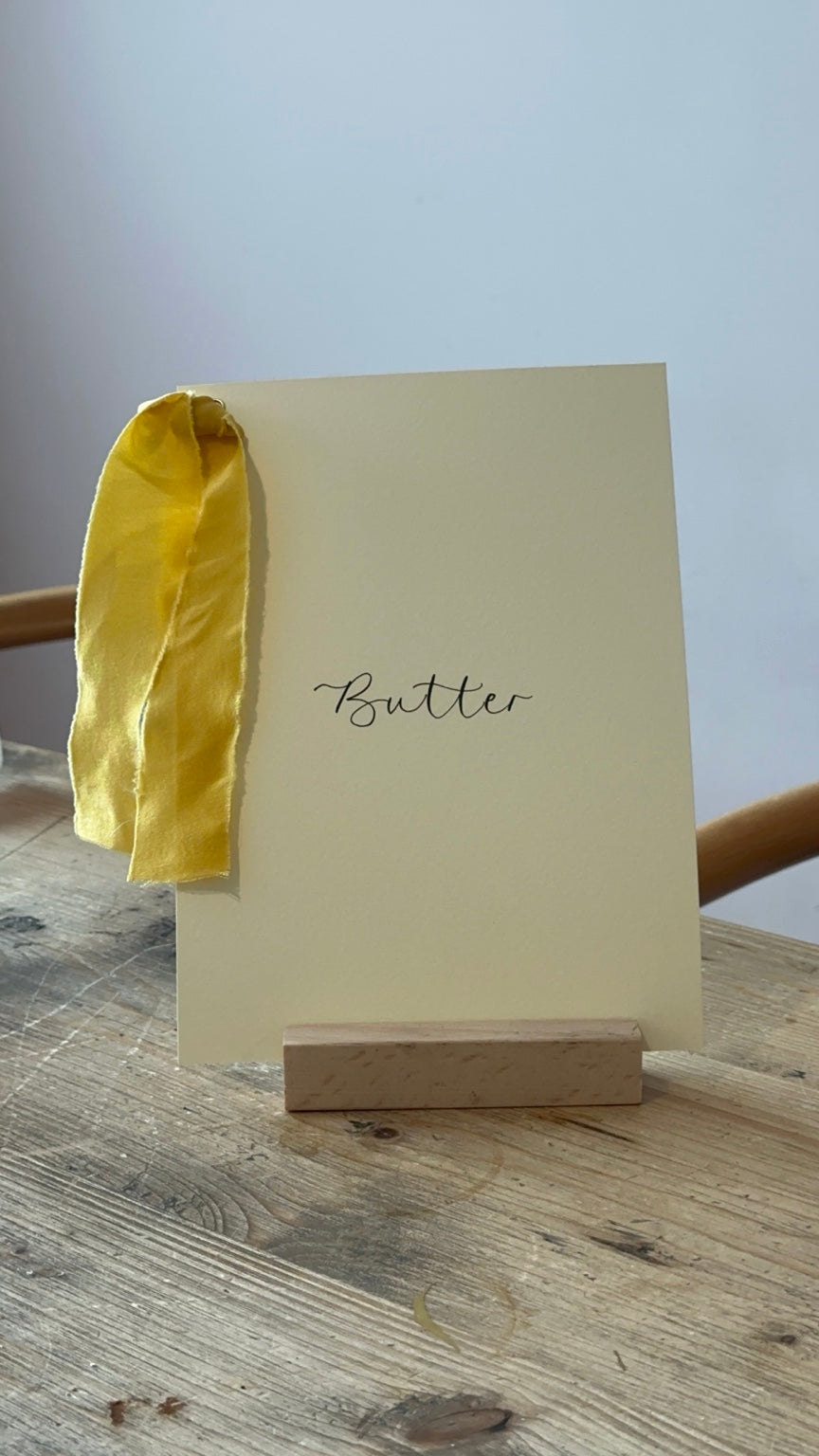 Butter yellow wedding table name sign with yellow ribbon and black calligraphy